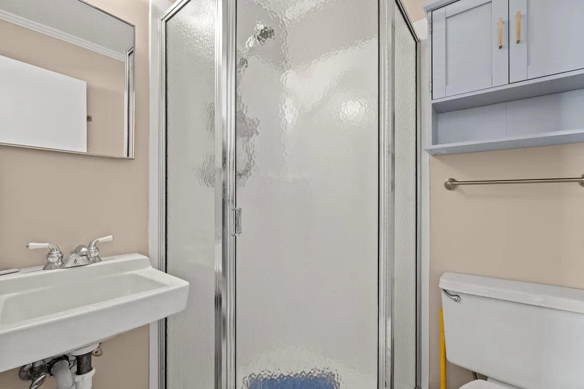 A fresh, efficient bathroom with a shower stall, sink, mirror, and storage cabinet. The clean design and practical amenities make it easy for everyone to get ready or wind down in comfort.